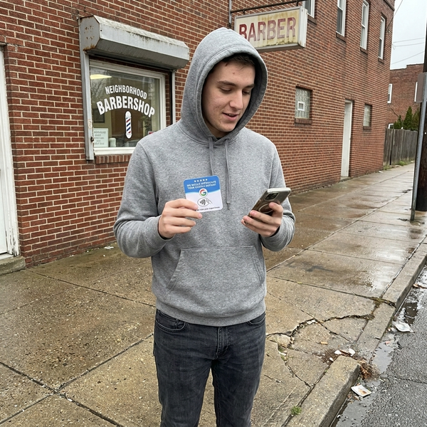 Side hustler holding a review card outside a barbershop